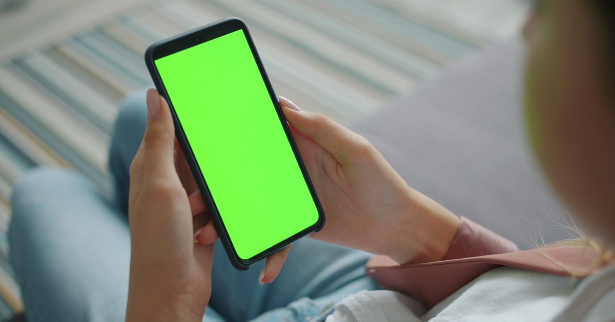 A woman holding a smartphone up to the camera, the setup most nail techs use when editing nail photos in CapCut