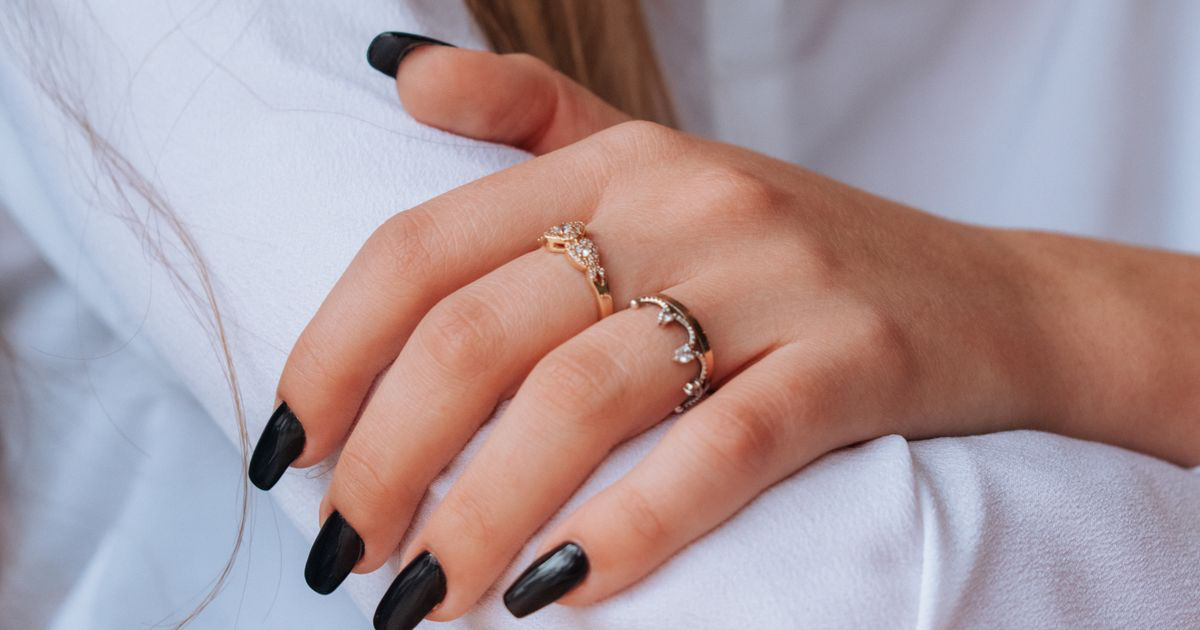 Close-up of a hand with glossy black nails and silver rings, the kind of dark set that needs careful editing to keep black nail photos from turning grey