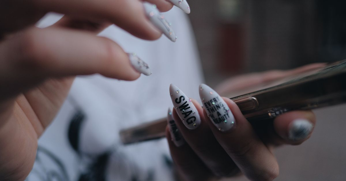 A close-up of detailed nail art on a hand holding a smartphone, the scale most nail art photos are viewed at