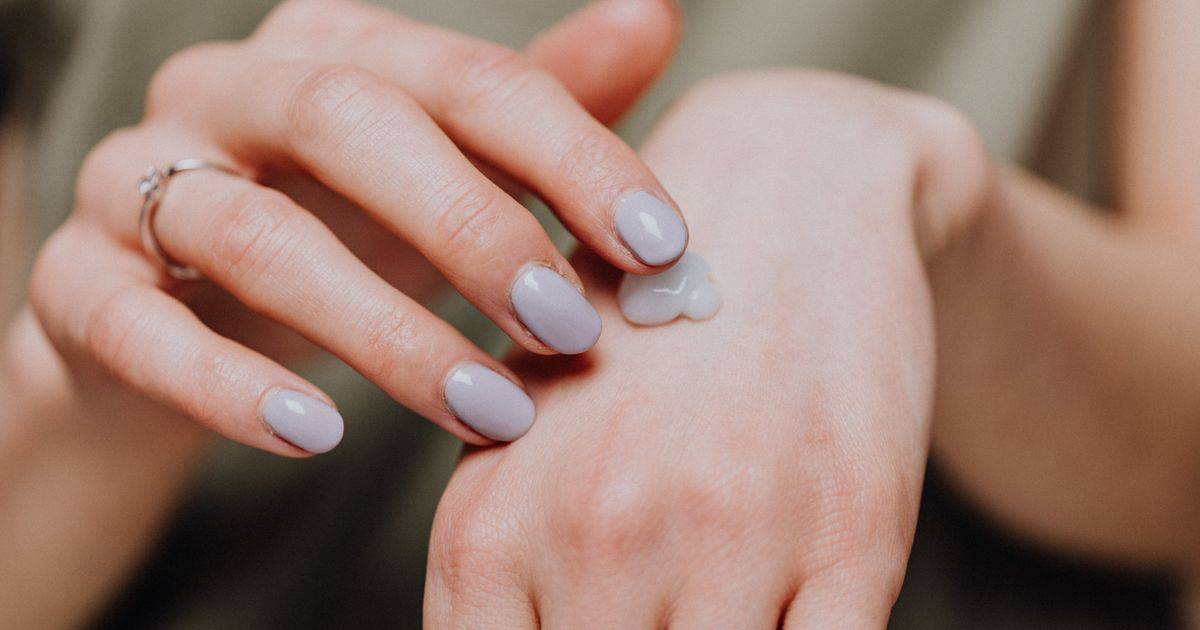 A manicured hand rubbing in hand cream, the oil and cream that cause shiny hands in nail photos