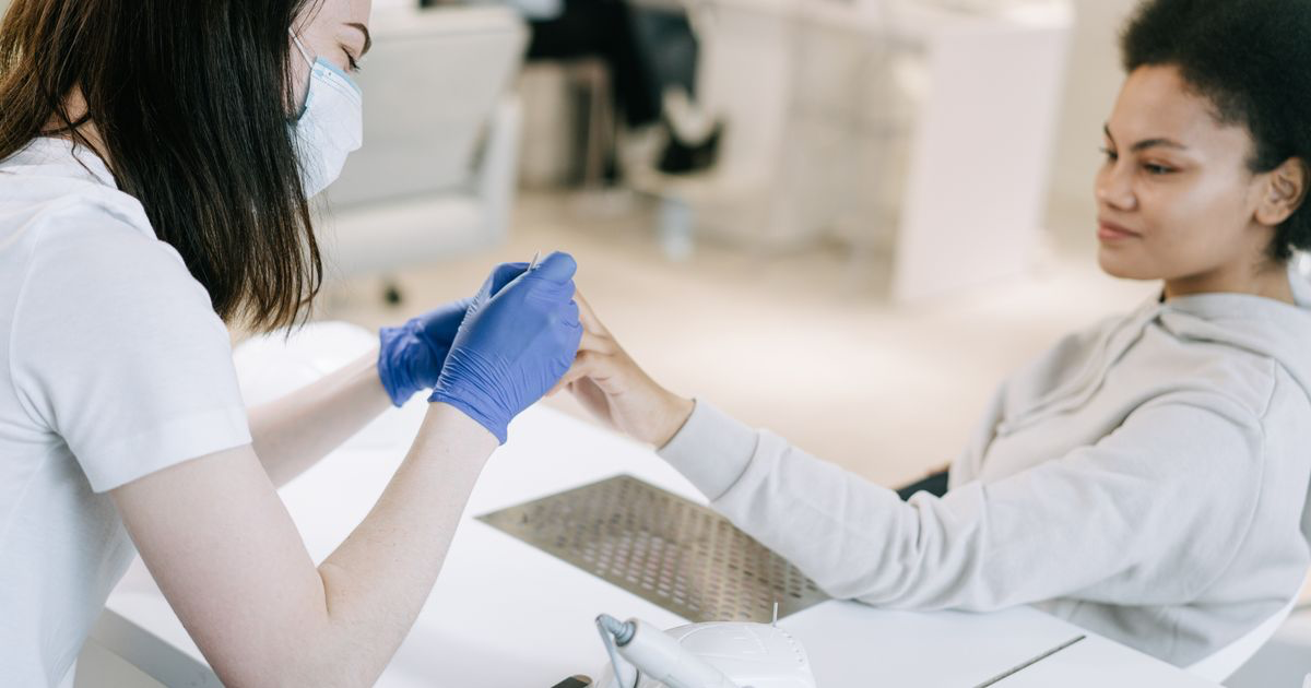 Nail technician doing a client's nails at a salon table, the conversation where an unhappy nail client can still be won back