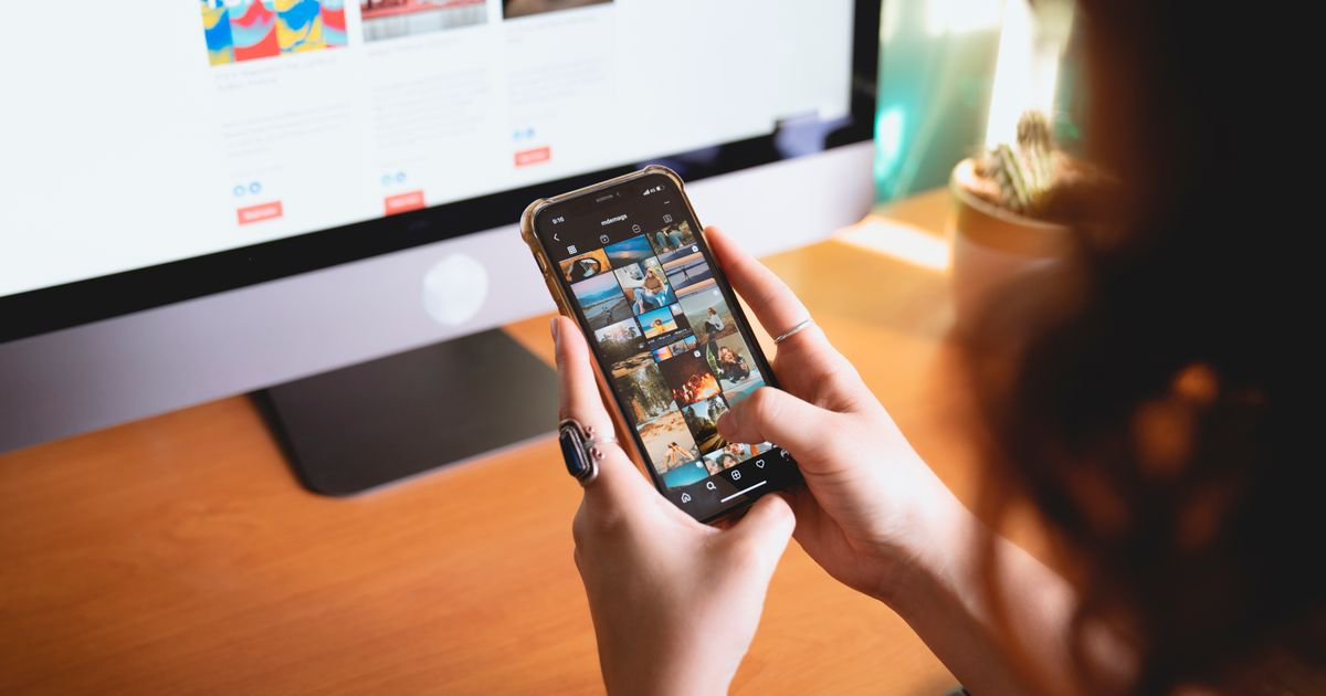 A person browsing photos on a smartphone at a desk, where most nail photo editing mistakes get made