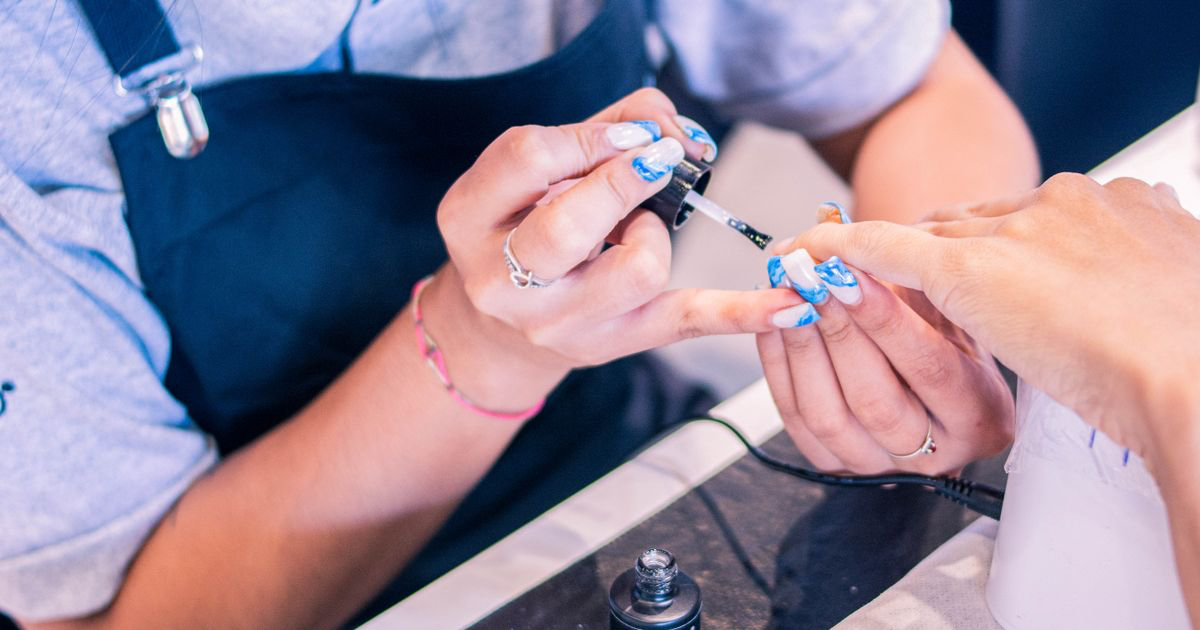 A nail artist applying polish to a client in a salon, the kind of work that ends up in a nail portfolio