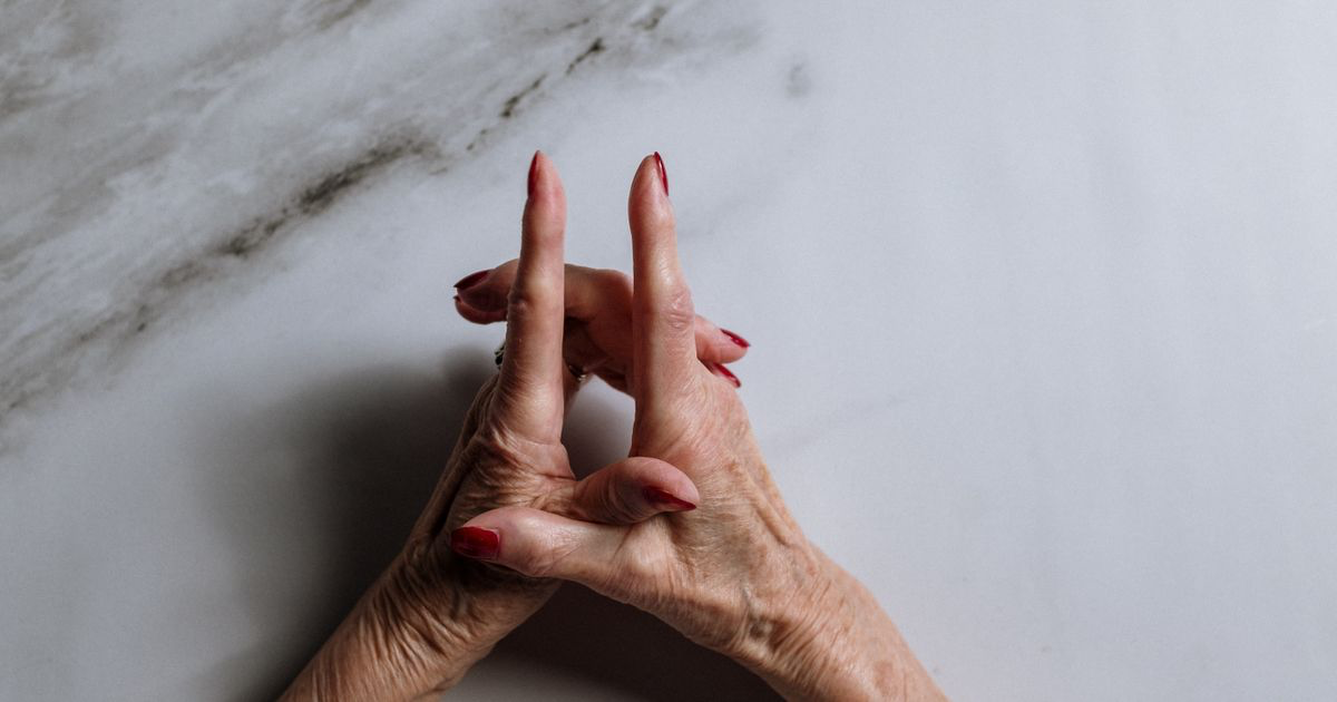 A hand with a manicure resting on a plain pale surface, showing how to add a white background to nail photos
