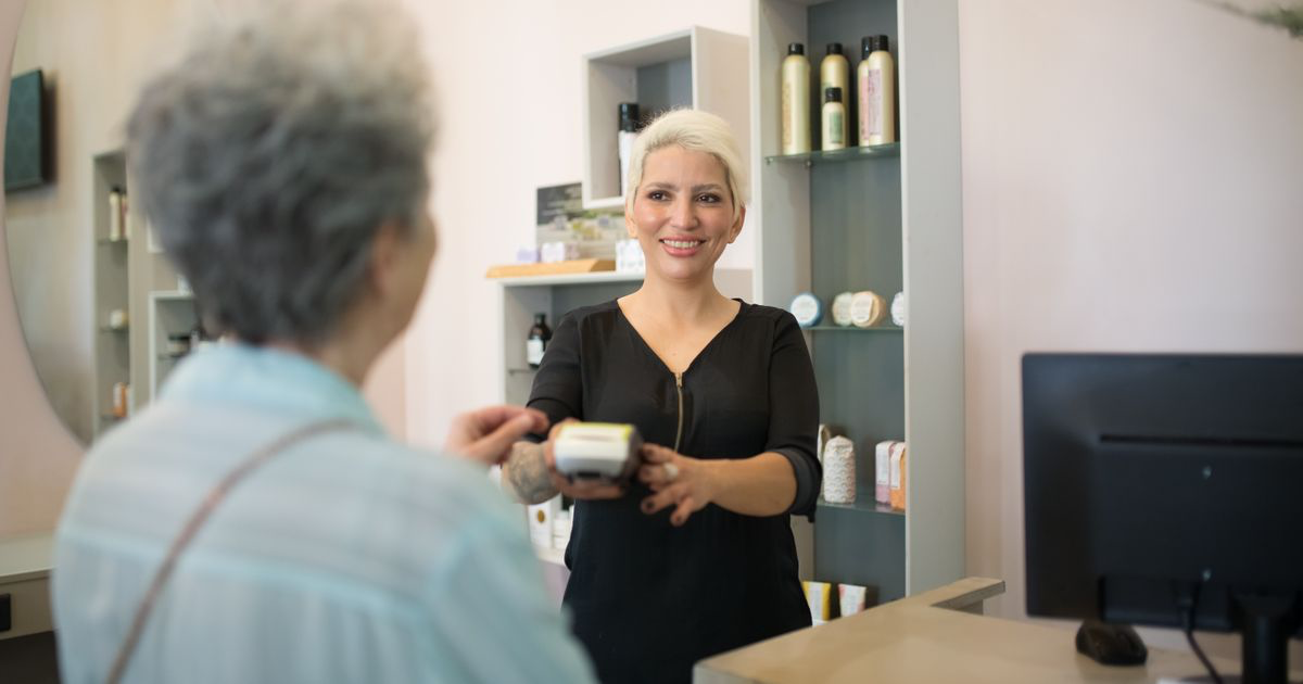 Salon professional with a client at the payment desk, the moment to announce a price increase to nail clients