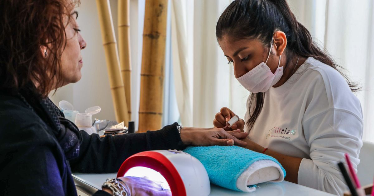 Nail technician giving a manicure at a table, the setup a mobile nail tech recreates in a client's home