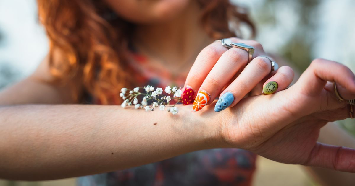 Close-up of a hand with long nails and colourful nail art, the kind of acrylic set this editing guide covers