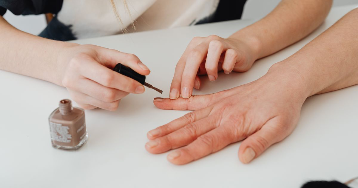 Close-up of a manicure in progress under warm salon lighting, the conditions behind how to edit brown nail photos