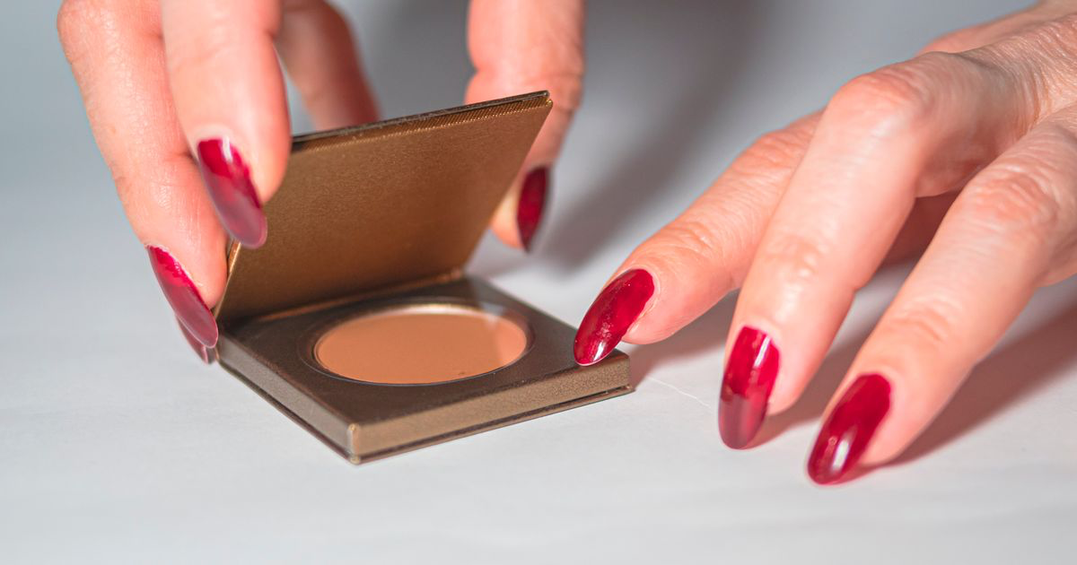 Close-up of a manicured hand with painted nails holding a makeup compact, the kind of salon shot to edit matte nail photos from