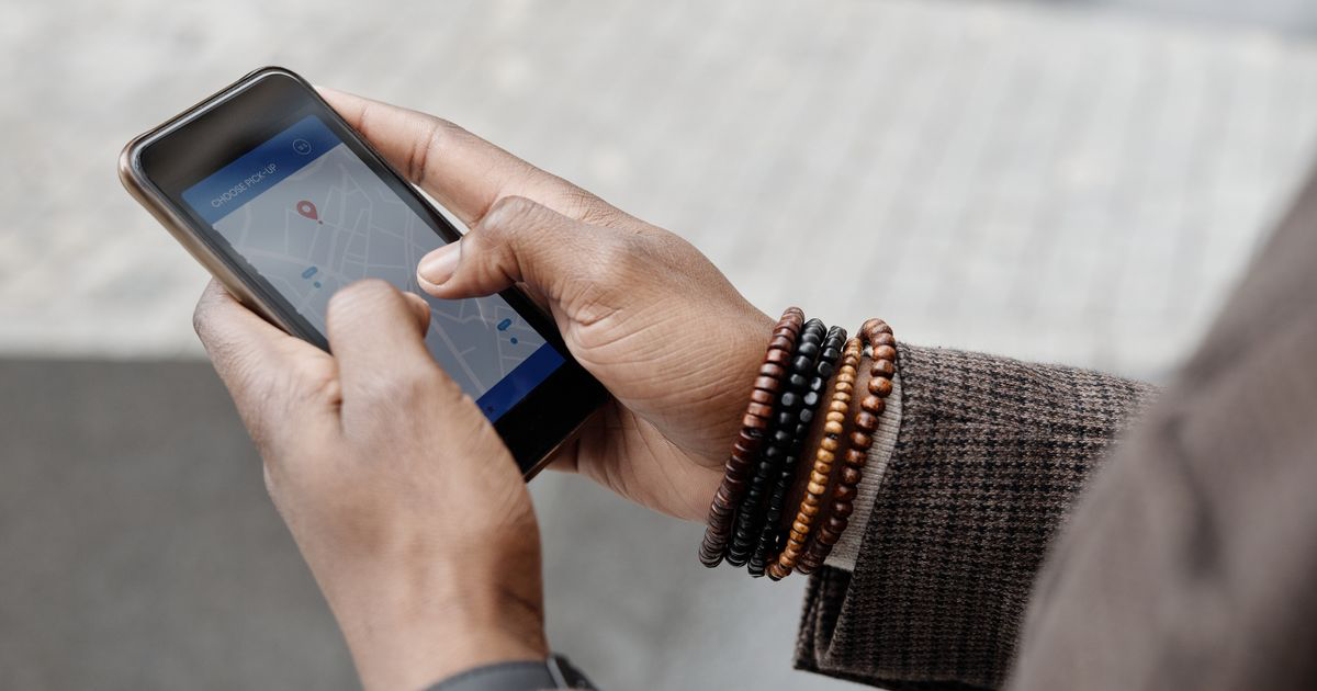 Close-up of hands wearing bracelets using a maps app on a smartphone, illustrating how to edit nail photos for Google Business Profile