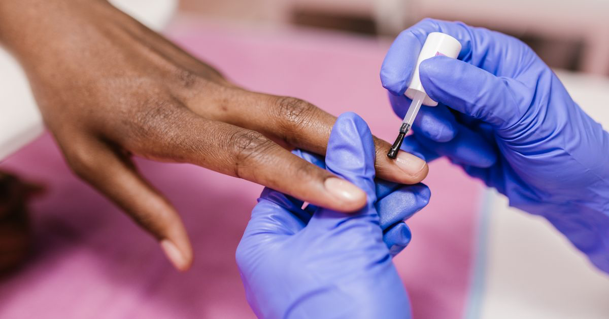 Close-up of a manicure being filed and polished in a salon, the kind of set covered in how to edit purple nail photos