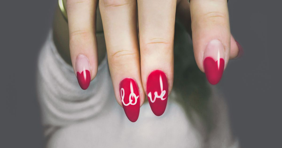 Close-up of a glossy red manicure with white nail art on a woman's hand, the kind of red set this editing guide corrects
