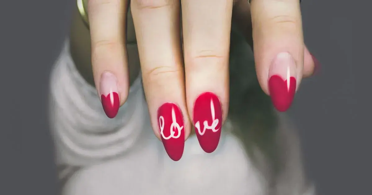 Close-up of a glossy red manicure with white nail art on a woman's hand, the kind of red set this editing guide corrects