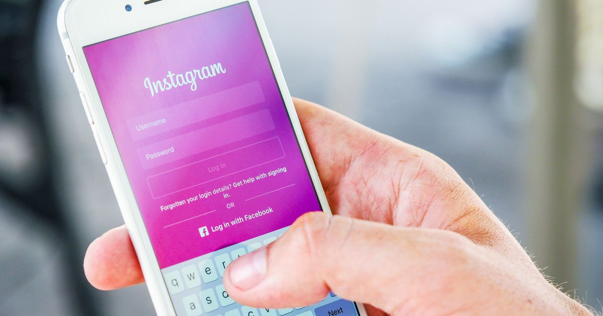 Nail tech holding a smartphone with the Instagram login screen, ready to edit an Instagram bio